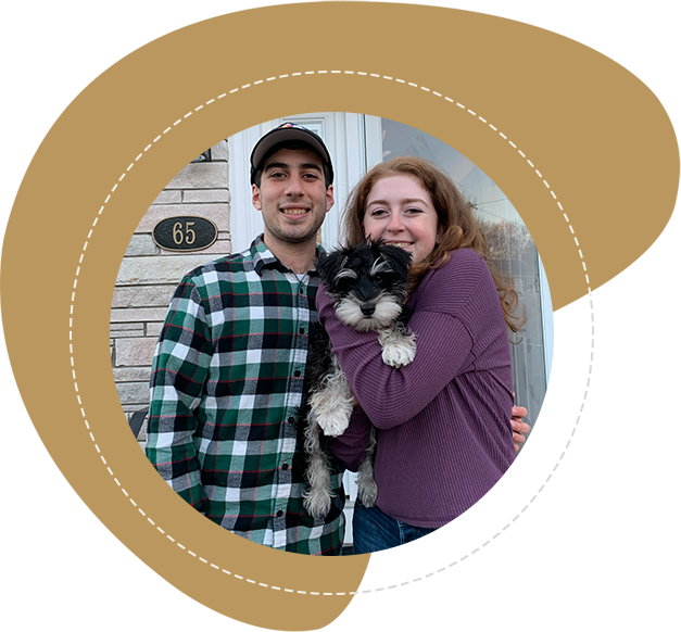 A man and woman holding a dog in front of a building.